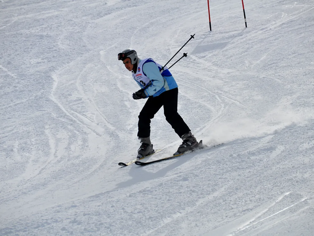 Skifahrerin fährt mit angelegten Stöcken die Strecke hinunter.